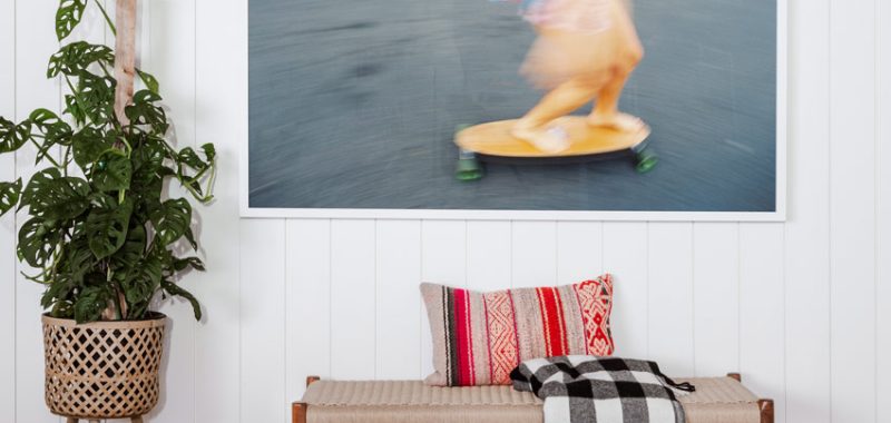 A vibrant and dynamic skateboarding scene captured as a blurred motion picture on a white wall, complementing a cozy living space with houseplants and stylish decor.
